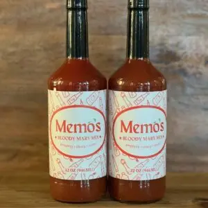 Two bottles of sauce on a wooden table.