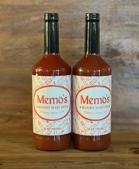 Two bottles of sauce on a wooden table.