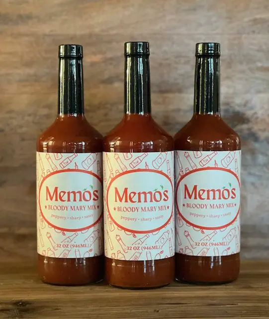 Three bottles of sauce on a wooden table.