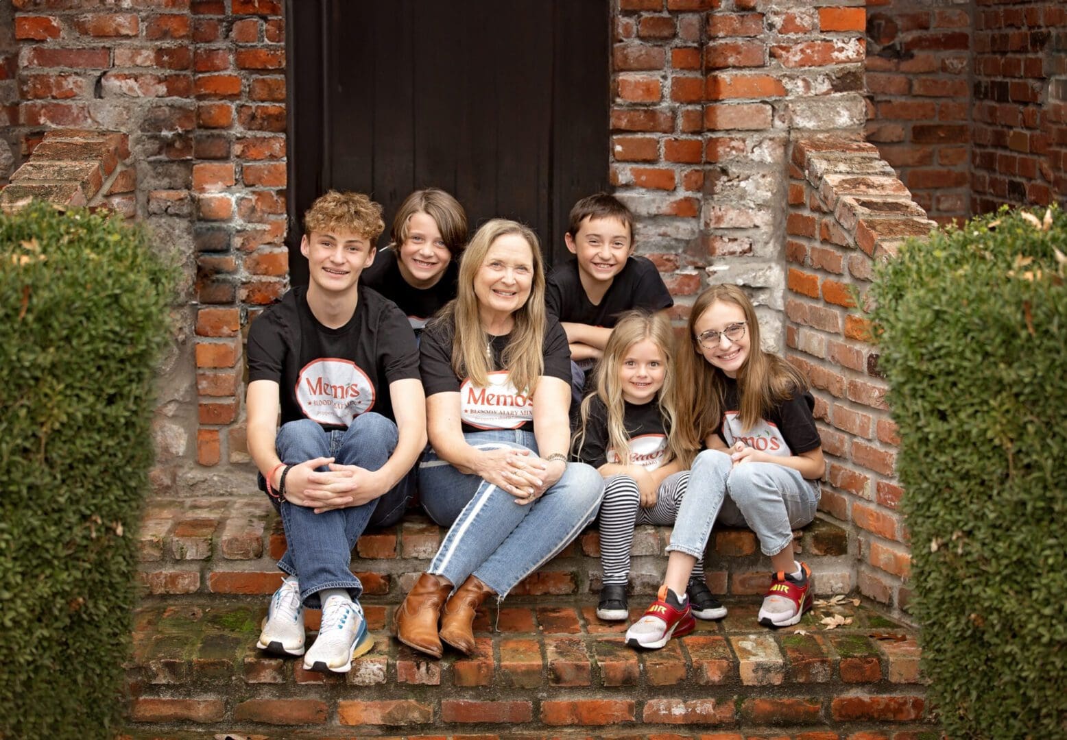 A group of people sitting on steps in front of a brick building.